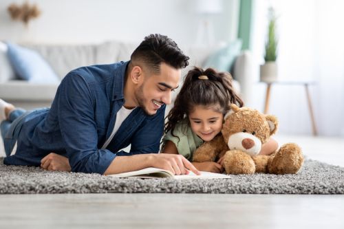 Loving divorced dad reading book with his little daughter at home. Visual concept for a family law blog discussing how Minnesota’s updated parenting time laws under House File 3204 impact custody, spousal maintenance, and parental rights.